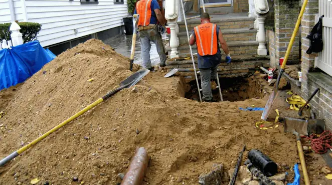Contractors performing foundation protection and exterior drainage excavation near residential home steps in ,